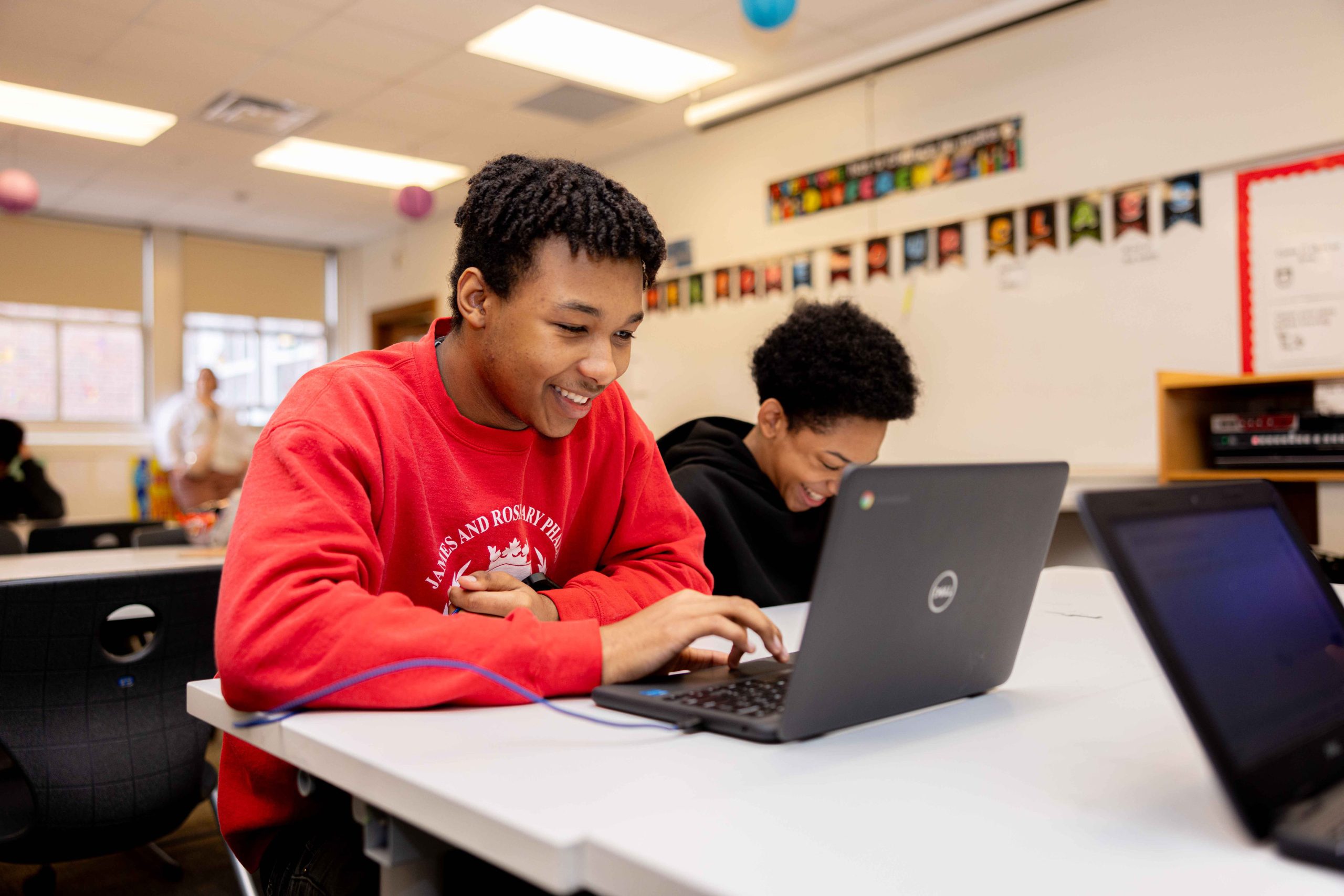 Two students, one in foreground looking at laptop