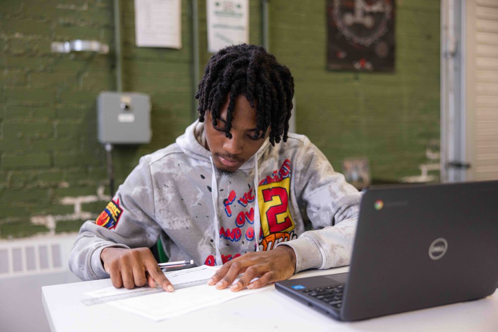 Student looking at paper with a laptop