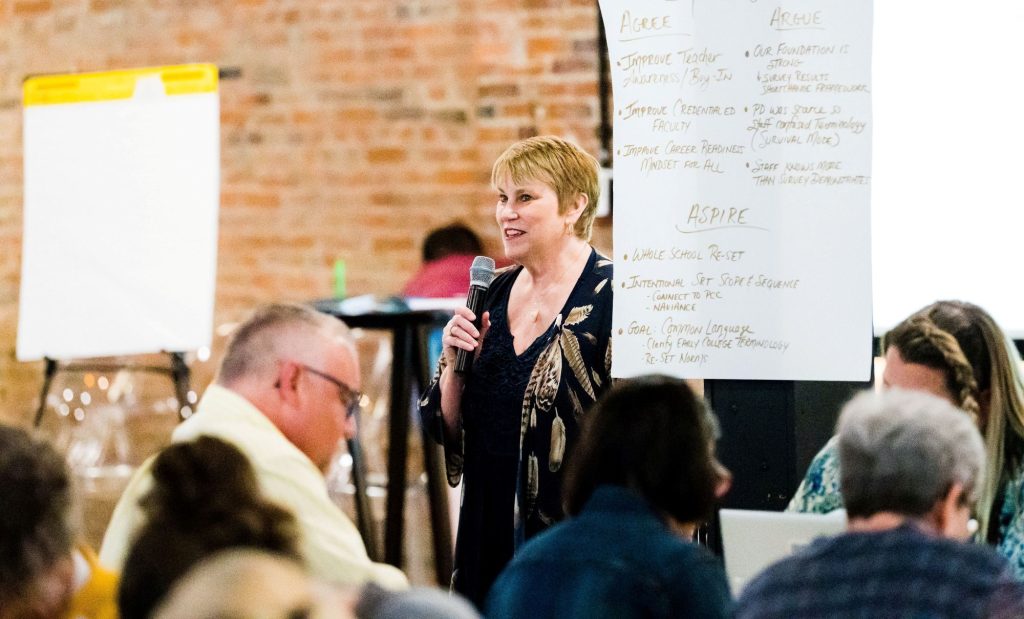 Person speaking with microphone next to notes