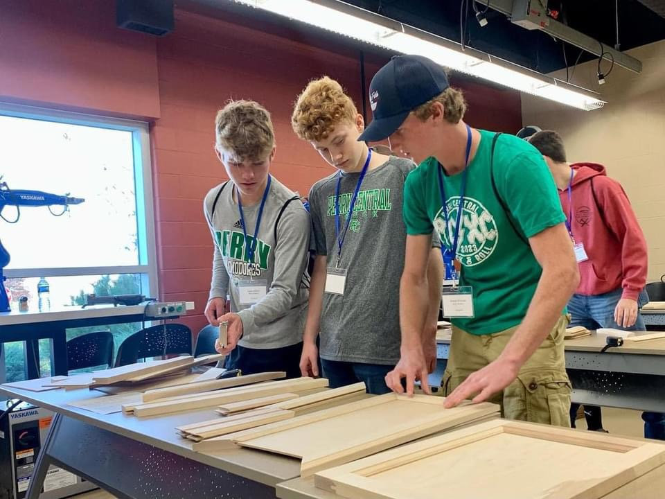 Three students working on cabinets