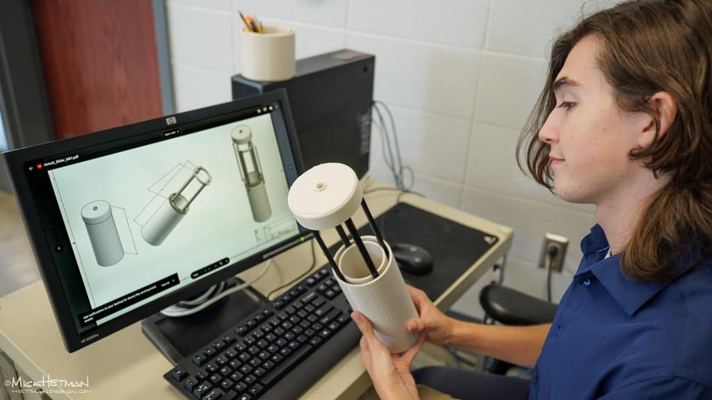 Student holding prototype with computer showing prototype models