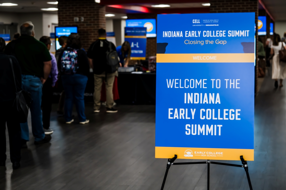Sign with Welcome to the Indiana Early College Summit and people in registration line