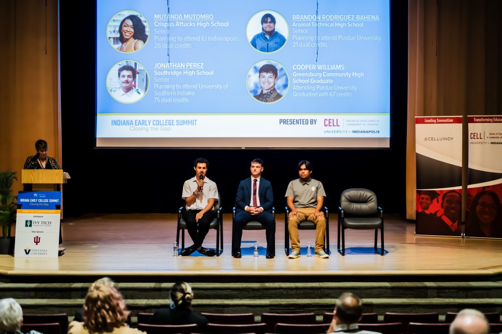 Three student panelists on chairs, one with microphone